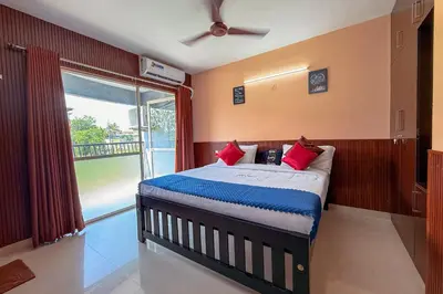 a bedroom with a bed with red pillows and a window at Stella Marries Airpot Lounge in Nedumbassery