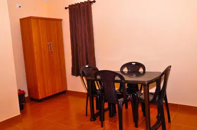 a dining room with a table and four chairs at Palm Resort in Gūdalūr