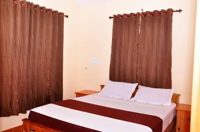 a bedroom with a bed with brown curtains at Palm Resort in Gūdalūr
