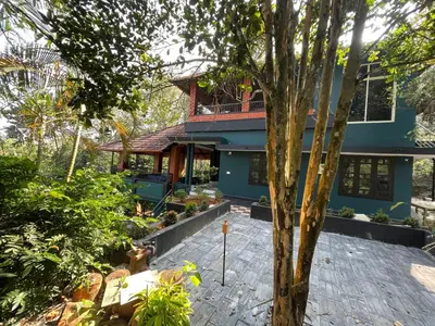 a blue house with a tree in front of it at CASTELLO Holiday Villa in Kalpetta