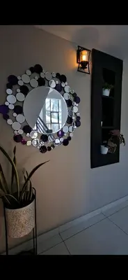 a mirror hanging on a wall with a plant at Grand UNX in Kannur
