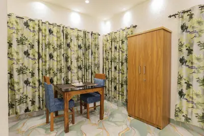 a room with a table and chairs and curtains at Velvet Oasis Cottages in Vythiri