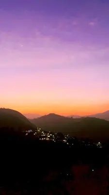 a sunset in the mountains with a city at Casa De KCN in Kotagiri