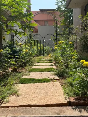 a garden with a walkway in front of a gate at Sogni D oro in Mysore
