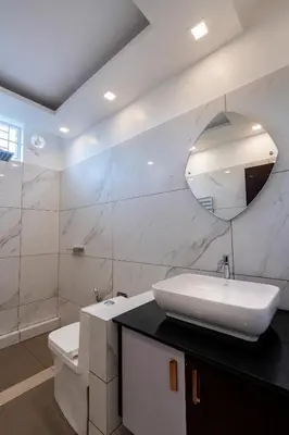 a white bathroom with a sink and a mirror at Cochin Airport Hotel in Ernakulam