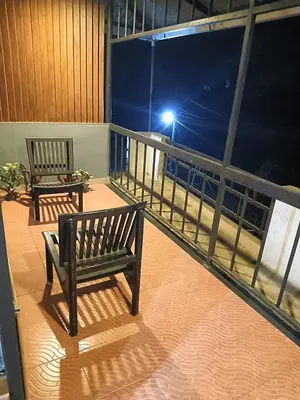 two benches sitting on a balcony at night at Tea vista holiday home in Kalpetta