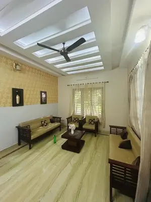 a living room with couches and a ceiling fan at Stay Easy - Potta, Athirapally Road in Kizhake Chālakudi