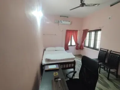 a small room with a bed and a table and chairs at Katadi beach homestay in Trichūr