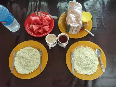 a table topped with plates of food with eggs and fruit at Katadi beach homestay in Trichūr