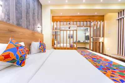 a bedroom with a large white bed with colorful pillows at FabHotel INK - Nr Coimbatore North Railway Station in Coimbatore