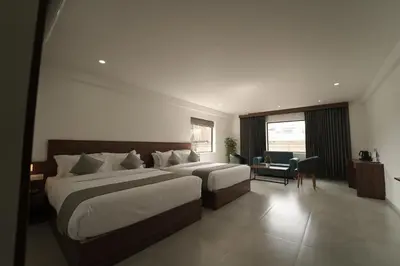 a hotel room with two beds and a desk at Georjoys Hotels & Resorts in Kalpetta