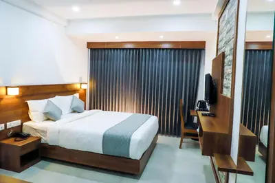 a bedroom with a bed and a desk and a television at Georjoys Hotels & Resorts in Kalpetta