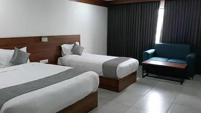 a hotel room with two beds and a chair at Georjoys Hotels & Resorts in Kalpetta