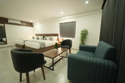 a bedroom with a bed and a table and chairs at Georjoys Hotels & Resorts in Kalpetta