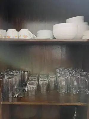 a shelf filled with glasses and plates and bowls at RiverSoul Villa in North Paravur