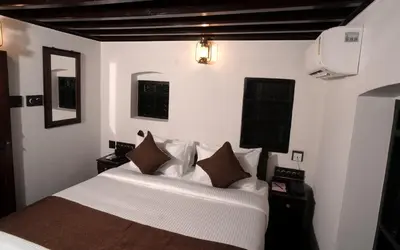 a bedroom with a bed with white sheets and brown pillows at Krishnapuram Heritage Resort in Karimpuzha