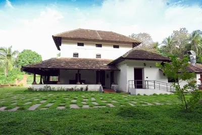 a house with a green lawn in front of it at Krishnapuram Heritage Resort in Karimpuzha