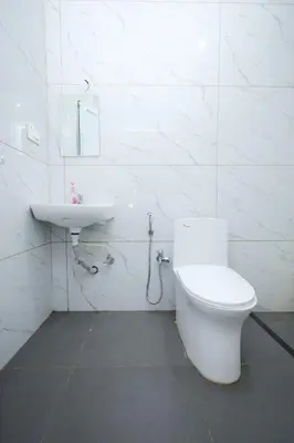 a white bathroom with a toilet and a sink at Travel & Stay in Ooty