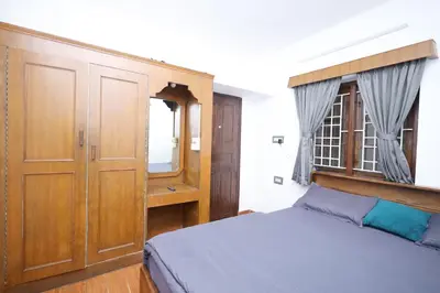 a bedroom with a bed and a wooden cabinet at Travel & Stay in Ooty