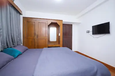 a bedroom with a large bed and a television at Travel & Stay in Ooty