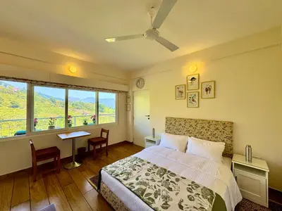 a bedroom with a bed and a desk and a window at Jade Pearl Kotagiri in Kotagiri