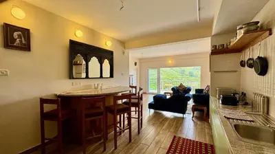 a kitchen and living room with a table and chairs at Jade Pearl Kotagiri in Kotagiri