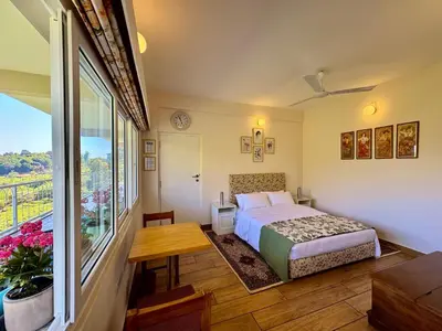 a bedroom with a bed and a table and a window at Jade Pearl Kotagiri in Kotagiri