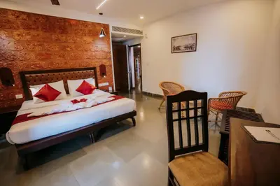 a bedroom with a bed and a table and chairs at Nirmallyam Residency Hotel in Edappāl