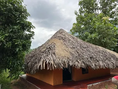 a hut with a thatched roof on top of it at Jungle Farm House in Kollengode