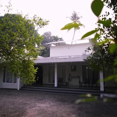 a white house with a palm tree in the background at Nutmeg Haven Plantation stay in Chewarra