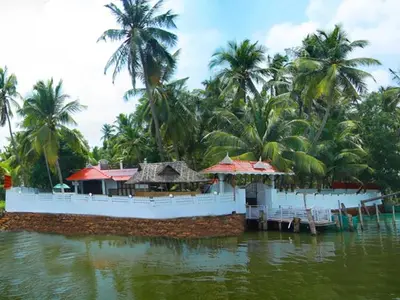 a house on a boat in a river with palm trees at karimeen hut in Irimbranallūr