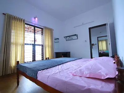 a bedroom with a large bed and a large window at karimeen hut in Irimbranallūr