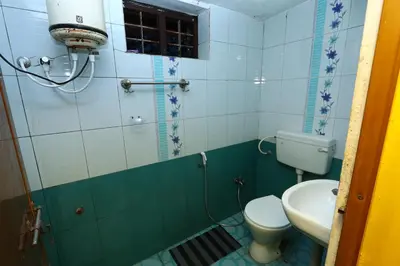 a bathroom with a toilet and a sink at Hillside Green Valley Comfort Stay in Gūdalūr
