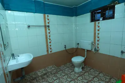 a bathroom with a toilet and a sink at Hillside Green Valley Comfort Stay in Gūdalūr