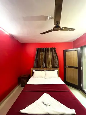 a red bedroom with a bed with a ceiling fan at Hillside Green Valley Comfort Stay in Gūdalūr