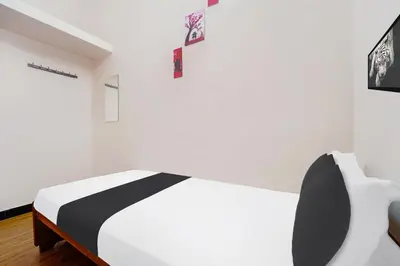 a white bedroom with a black and white bed at Super Hotel O Ganapathy Athipalayam Pirivu Road in Coimbatore