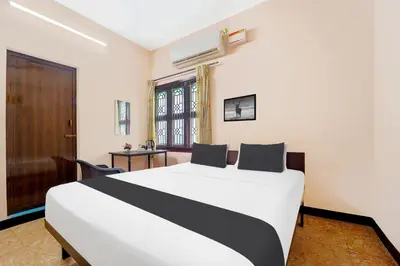 a bedroom with a large white bed and a window at Super Hotel O Ganapathy Athipalayam Pirivu Road in Coimbatore
