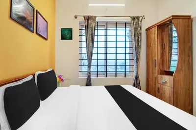 a bedroom with a bed and a window at Super Hotel O Rose Garden Ooty Formerly New Star Cottages in Ooty
