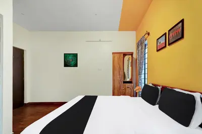 a bedroom with a white bed with black and yellow walls at Super Hotel O Rose Garden Ooty Formerly New Star Cottages in Ooty