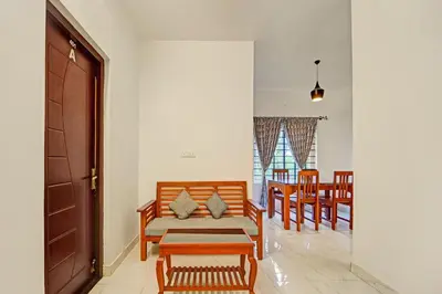 a living room with a couch and a table and chairs at Super Hotel O Rose Garden Ooty Formerly New Star Cottages in Ooty