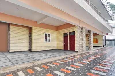 a yellow building with a red door on a sidewalk at Super Hotel O Rose Garden Ooty Formerly New Star Cottages in Ooty