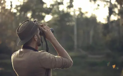 a man with a hat taking a picture with a camera at Coorg Wild Walk, Nagarhole - A CGH Earth SAHA Experience in Srimangala