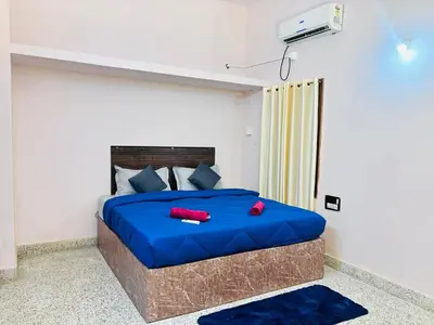 a bedroom with a bed with blue sheets and red pillows at Majestic Villa 5 Bedrooms AC Bunglow in Mysore