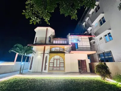 a large white house with a palm tree in front of it at Majestic Villa 5 Bedrooms AC Bunglow in Mysore