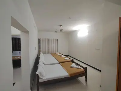 a room with a bed with white sheets on it at Dormitory Elite in Mysore