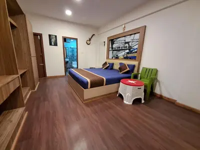 a bedroom with a bed and a green chair at Labony House in Kodaikānāl