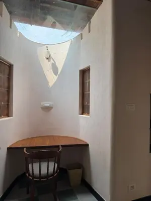 a table and a chair in a room with a ceiling at EcoMinimalist Home by the River in Seringapatam