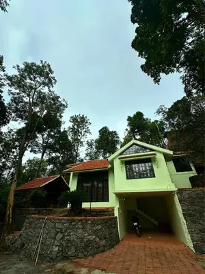 a green house with a brick driveway at Hazel and Oak in Vythiri