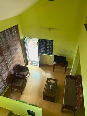 a living room with two chairs and a piano at Hazel and Oak in Vythiri