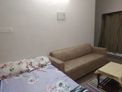 a living room with a bed and a couch at Homestay Guruvayur, 1 AC & 1 Non AC bedroom in Guruvāyūr
